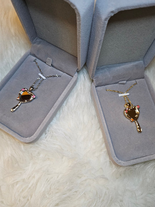 Mirror of Venus Necklace displayed in two elegant jewelry boxes on fluffy surface.