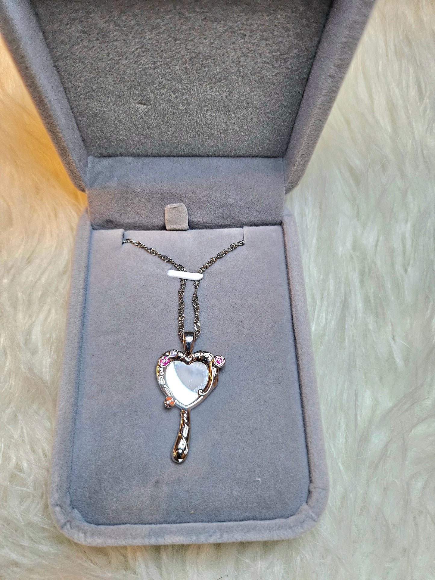 Mirror of Venus Necklace displayed in a soft jewelry box with heart pendant design and pink accents.