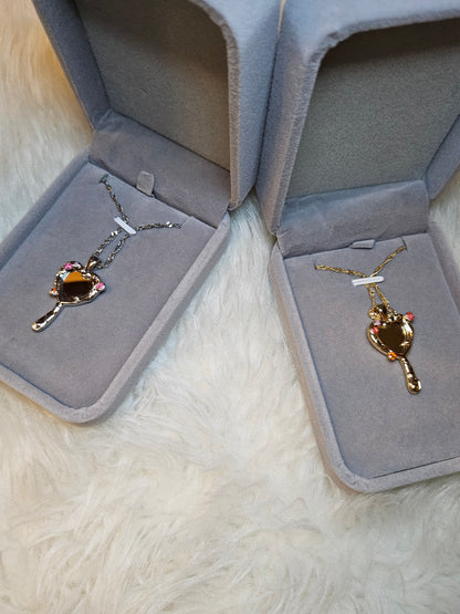 Mirror of Venus Necklace displayed in two elegant jewelry boxes on fluffy surface.