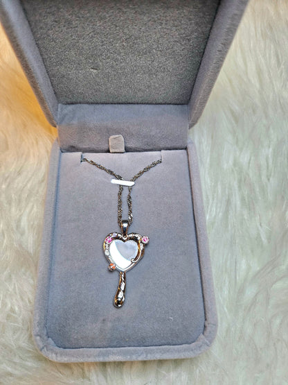 Mirror of Venus Necklace displayed in a soft jewelry box with heart pendant design and pink accents.